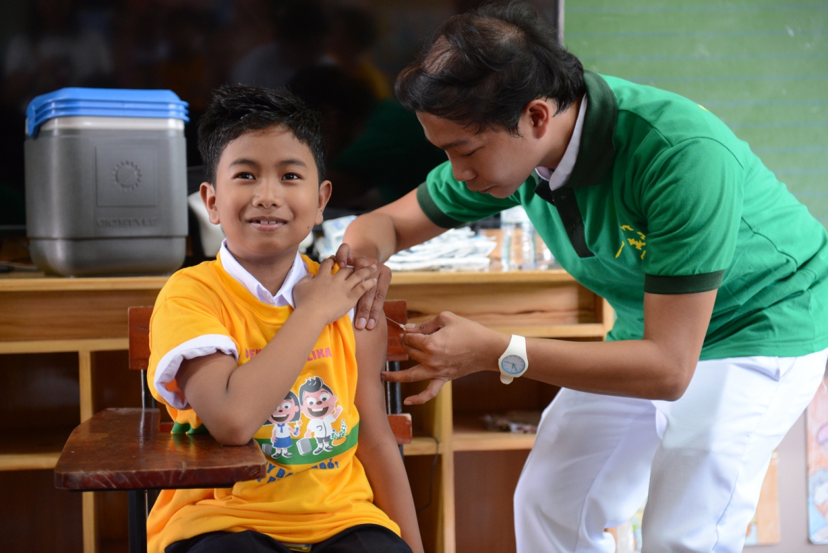 Image of a child in school getting a vaccinated following the recent WHO dengue vaccine recommendation.