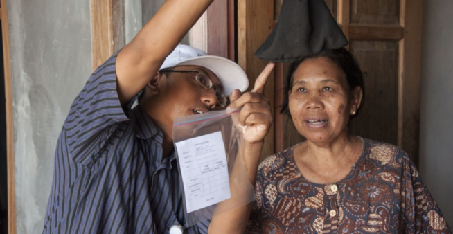 Image from one of the Wolbachia programs in Asia of a woman in Indonesia being shown the variety of mosquitoes caught during a monitoring program.