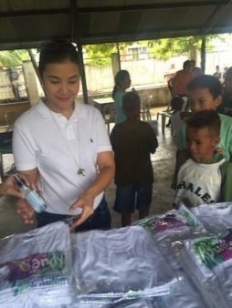 A woman from the Sandy project passes out anti-dengue kits in the Philippines. 